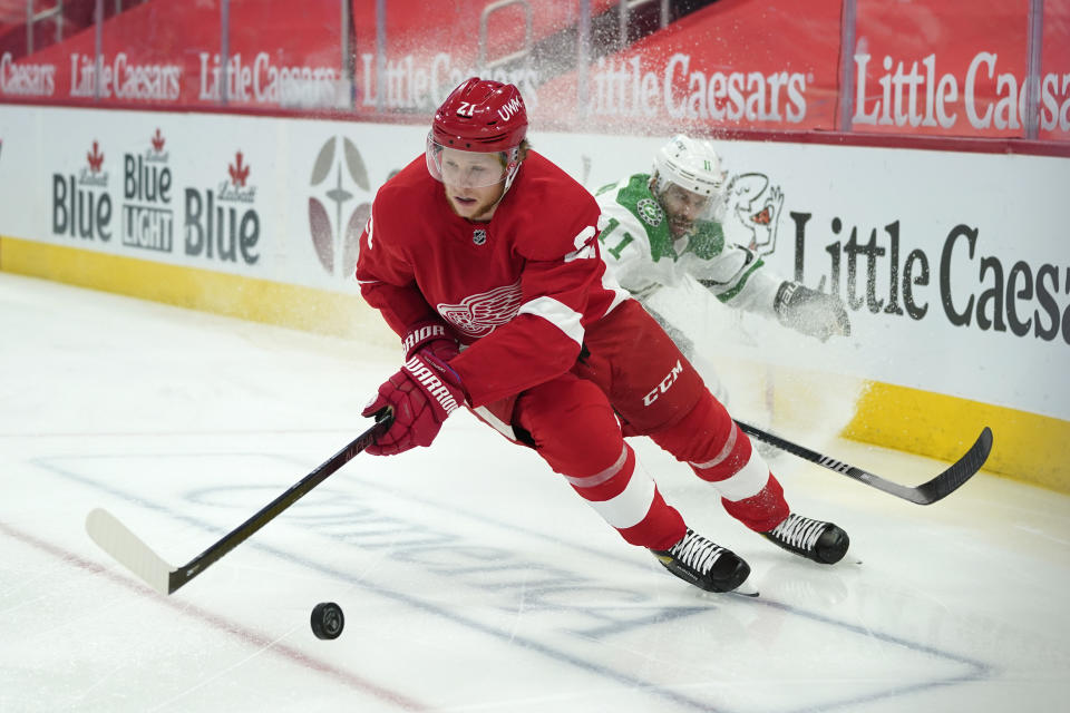 Detroit Red Wings defenseman Dennis Cholowski (21) protects the puck from Dallas Stars center Andrew Cogliano (11) in the first period of an NHL hockey game Thursday, April 22, 2021, in Detroit. (AP Photo/Paul Sancya)