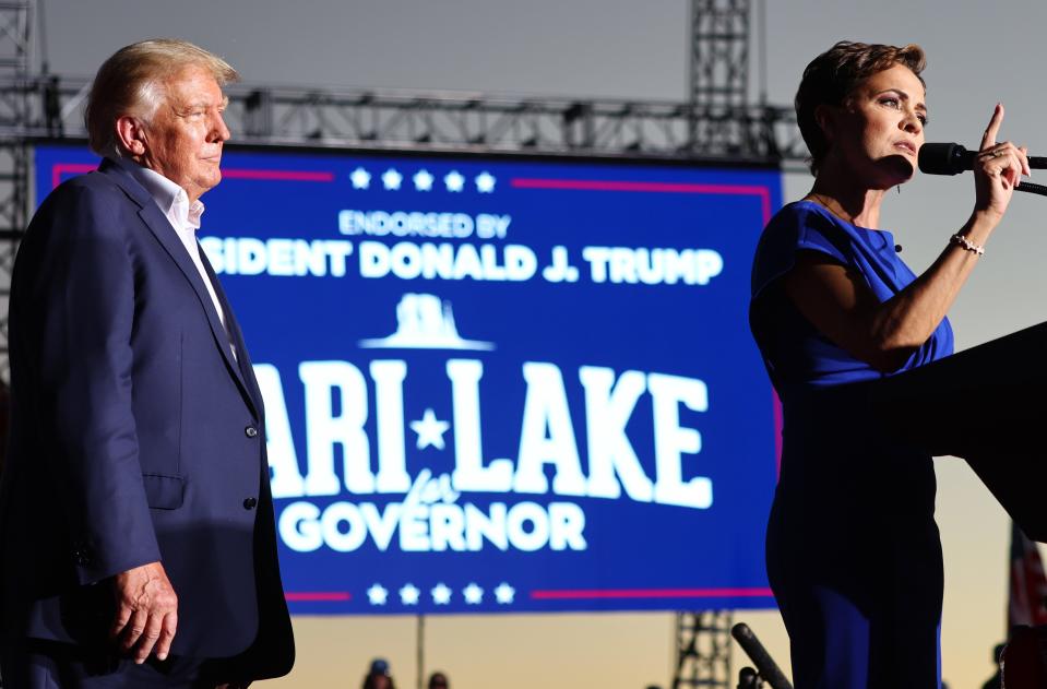Former U.S. President Donald Trump looks on as then-Arizona Republican nominee for governor Kari Lake speaks during a campaign rally on Oct. 9, 2022, in Mesa, Arizona.
