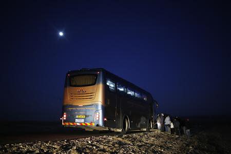 African migrants stand next to a bus as they are offered a one-way ride to a nearby city after abandoning a detention facility in the southern Israeli desert December 15, 2013. REUTERS/Amir Cohen