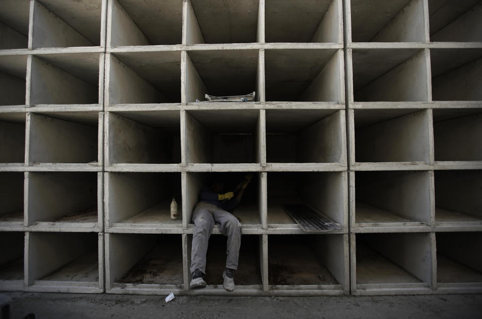 A worker builds niches at the Caju Cemetery in Rio de Janeiro, Brazil, Monday, April 20, 2020. There were already plans this year to create more tombs at Caju but the new coronavirus pandemic accelerated the construction. (AP Photo/Silvia Izquierdo)