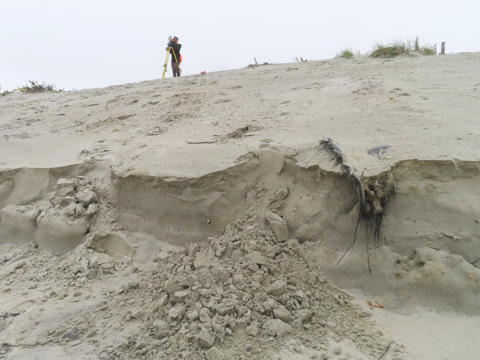 FILE - A worker from Stockton University surveys the contours of a newly reconstructed sand dune in North Wildwood, N.J., on Oct. 25, 2022. New Jersey filed a lawsuit Tuesday, Dec. 6, 2022 suing one of its shore towns that repaired damage from an October storm in defiance of a state order not to do so. (AP Photo/Wayne Parry, File)