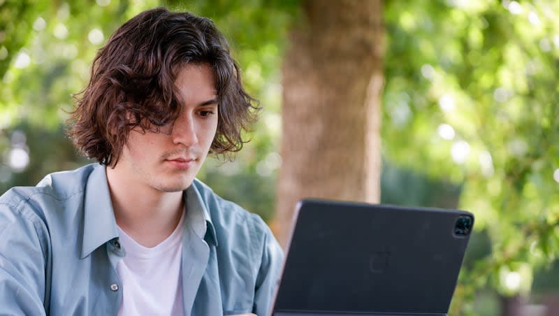 Jason Flechsing, a senior at Boise State University, does class work in Boise on Sept. 22, 2022. Sen. Mitt Romney is urging President Joe Biden to halt the latest plan for student debt relief.