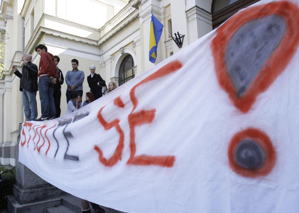 Students shout slogans near a banner that reads "Shame on you" in front of the National Museum, in Sarajevo, Bosnia, on Thursday, Oct. 4, 2012. Bosnia's 124 year-old National Museum closed its doors Thursday thanks to disputes among politicians and dwindling state funding. Having not received their salaries for a year, employees first gathered at the fountain in the Museum's botanical garden and threw a coin into it making a wish the institution will reopen soon. (AP Photo/Amel Emric)