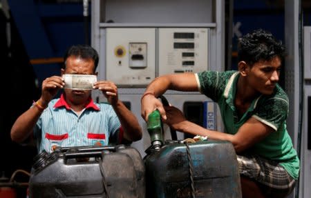 FILE PHOTO: A worker checks a 500 Indian rupee note as a man fills diesel in containers at a fuel station in Kolkata, India, August 14, 2018. REUTERS/Rupak De Chowdhuri