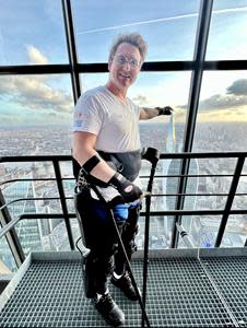 Simon Kindleysides stands at the top of the Leadenhall Skyscraper after a world-record breaking 51 story climb in his ReWalk Exoskeleton