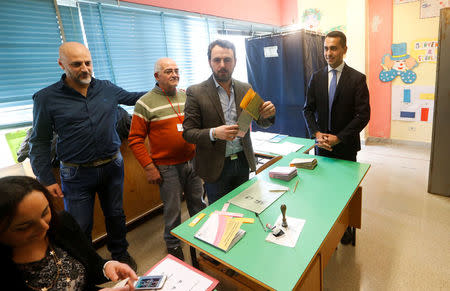 5-Star Movement leader Luigi Di Maio (R) receives his ballot as he prepares to cast his vote at a polling station in Pomigliano d'Arco, near Naples, Italy March 4, 2018. REUTERS/Ciro De Luca