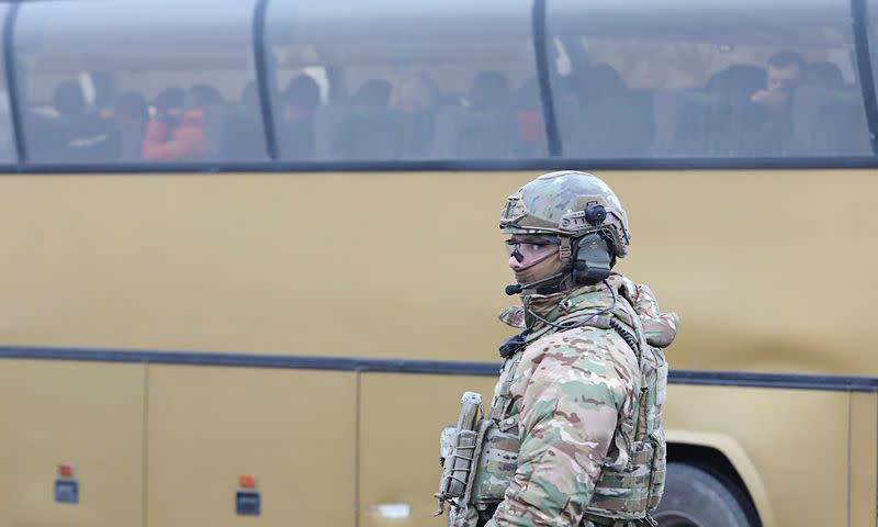 A Ukrainian serviceman stands guard near a bus during prisoner of war exchange in Donetsk region