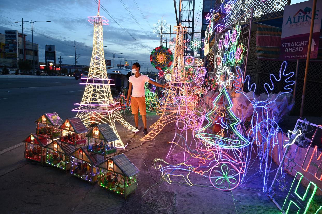 FILE PHOTO: This photo taken on October 6, 2020 shows a worker standing beside lanterns and lit ornaments, including several shaped in the likeness of the Eiffel Tower, for sale during the festive season at a shop in San Fernando town in Pampanga province. (Photo: TED ALJIBE/AFP via Getty Images)