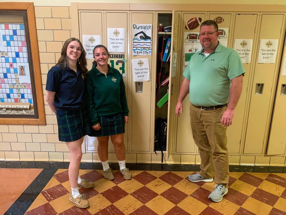 Senior Carrie Niemiec (left) and junior Ana Perna stand next to principal Joe Carroll in the hallway at St. Mary Catholic Central High School. Carroll is new at the school this year.