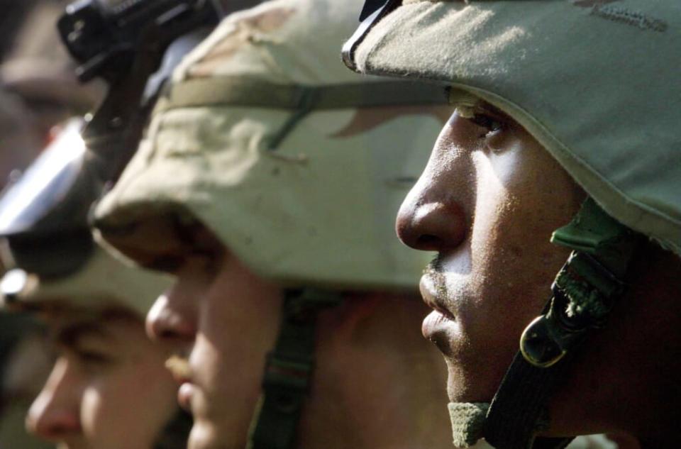 (Left to right) Unidentified U.S. Army 101st Airborne Division members and E4 Bobby (last name withheld) on Jan. 15, 2002, are stationed at the American military compound at Kandahar Airport in Kandahar, Afghanistan. (Photo by Mario Tama/Getty Images)