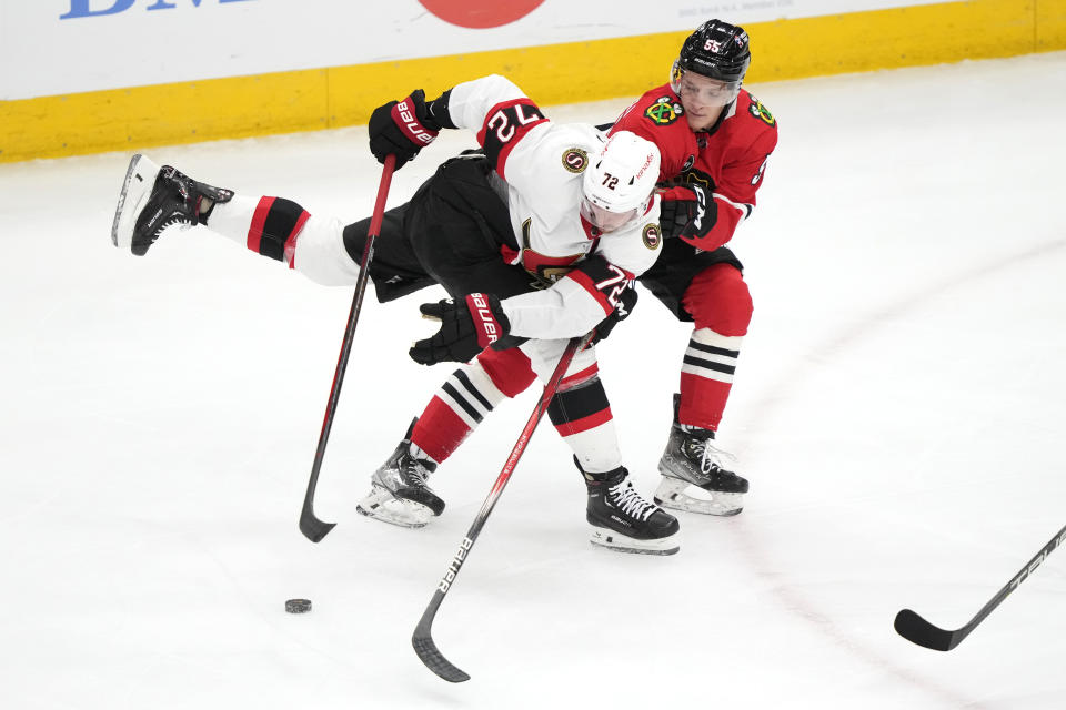 Ottawa Senators' Thomas Chabot loses control of the puck after being checked by Chicago Blackhawks' Kevin Korchinski during the first period of an NHL hockey game Saturday, Feb. 17, 2024, in Chicago. (AP Photo/Charles Rex Arbogast)