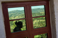 Saidy Aguilon is reflected in the window of a home in Comitancillo, Guatemala, Wednesday, Jan. 27, 2021. She believes that her husband is one of the charred corpses found in a northern Mexico border state on Saturday. The country's Foreign Ministry said it was collecting DNA samples from a dozen relatives to see if there was a match with any of the bodies. (AP Photo/Oliver de Ros)