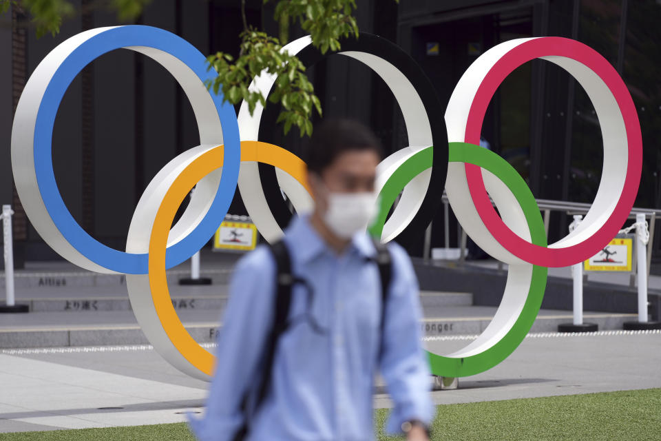 A man wearing a protective mask to help curb the spread of the coronavirus walks near the Olympic Rings Wednesday, June 2, 2021, in Tokyo. (AP Photo/Eugene Hoshiko)