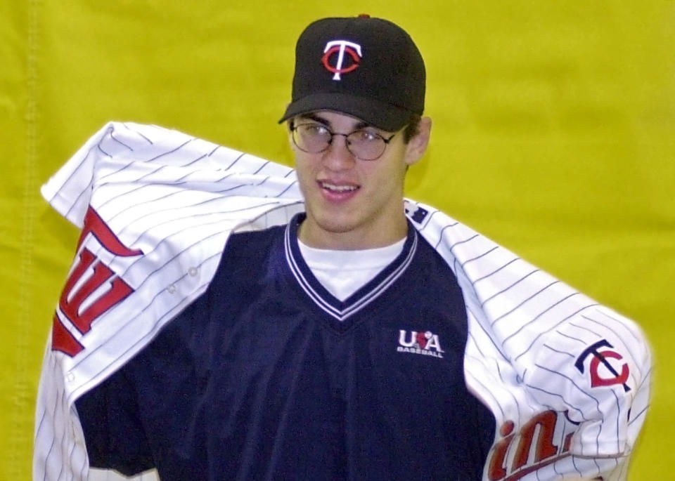 FILE - In this June 5, 2001, file photo, Joe Mauer puts on a Minnesota Twins jersey during a news conference at his high school in St. Paul, Minn., after he became the No. 1 overall pick in the Major League amateur draft. The Minneapolis Star Tribune reports that Mauer has taken out an ad in its Sunday, Nov. 11, 2018, paper to announce his retirement. (AP Photo/Jim Mone, File)