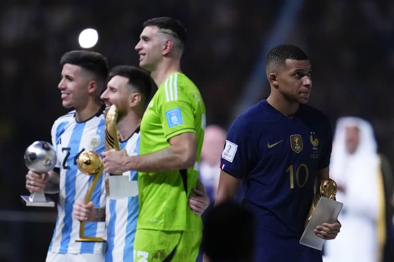 Kylian Mbappé (derecha) se marcha con su Botín de Oro, mientras posan con sus trofeos, de izquierda a derecha, los argentinos Enzo Fernández, Lionel Messi y Emiliano Martínez, luego de la final mundialista del domingo 18 de diciembre de 2022, en Lusail, Qatar