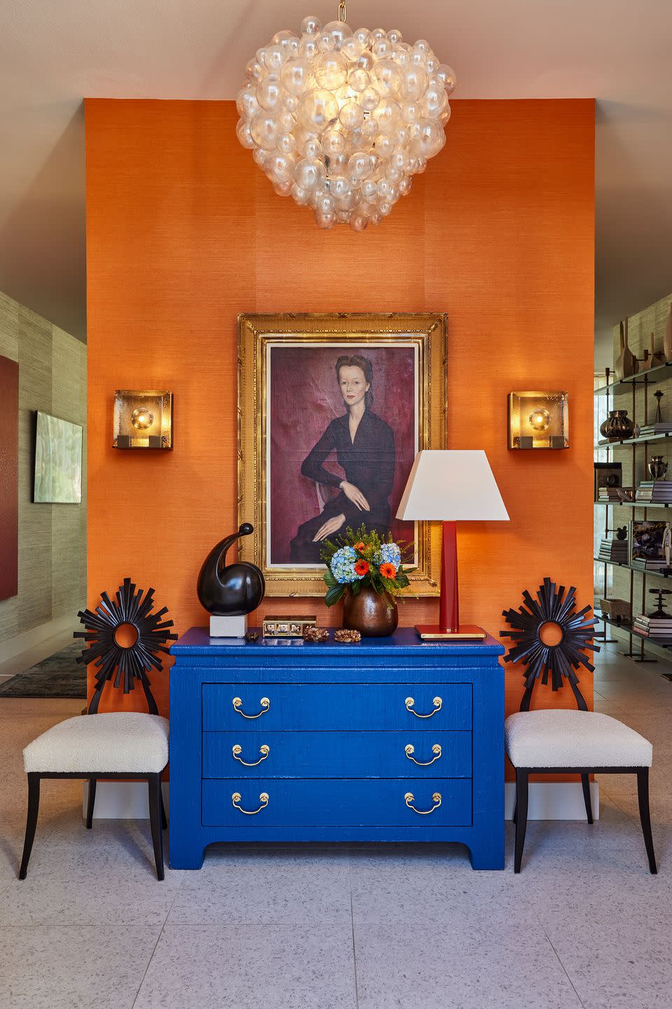 foyer with blue dresser and painting on an orange wall