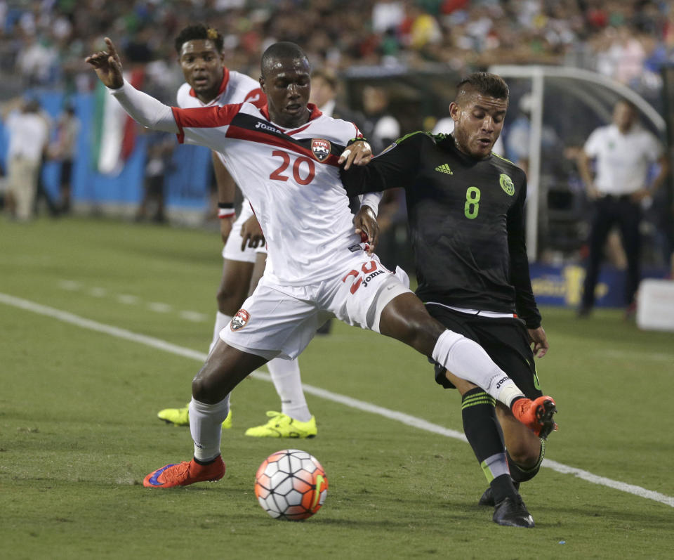 El mexicano Jonathan Dos Santos (8) disputa el balón con el trinitario Keron Cummings en el primer tiempo del partido de la Copa Oro de la CONCACAF en Charlotte, Carolina del Norte, el miércoles 15 de julio de 2015. Cummings anotó dos de los goles de Trinidad y Tobago en el empate de 4-4 ante México. (Foto AP/Chuck Burton)