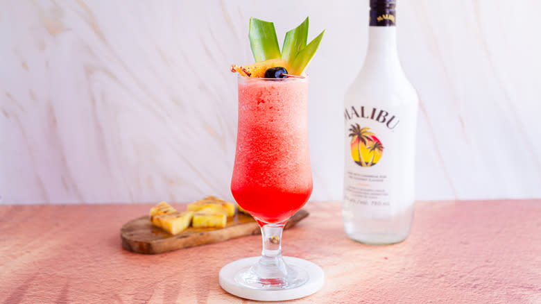 Frozen cocktail with garnish and Malibu rum in background