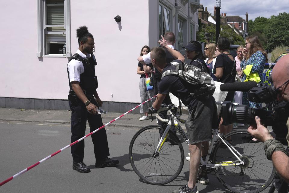 A police officer stands guard at a cordon line as a car crashed into a primary school building in Wimbledon, London, Thursday, July 6, 2023. London police say a girl died when an SUV crashed into an elementary school on a very narrow road in the Wimbledon district of southwest London. The Metropolitan Police said Thursday that there have been further injuries but did not provide details of how many. (AP Photo/Kin Cheung)