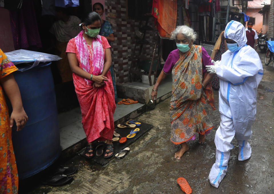 An elderly woman is helped by a health worker before screening her for COVID-19 symptoms in Dharavi, one of Asia's biggest slums, in Mumbai, India, Tuesday, Aug. 11, 2020. India has the third-highest coronavirus caseload in the world after the United States and Brazil. (AP Photo/Rafiq Maqbool)