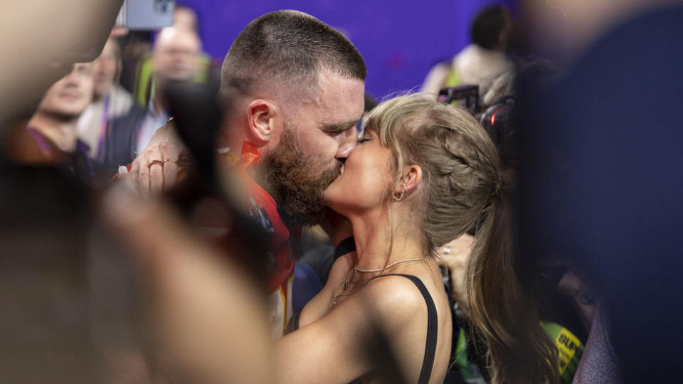 Taylor Swift and Travis Kelce kiss.