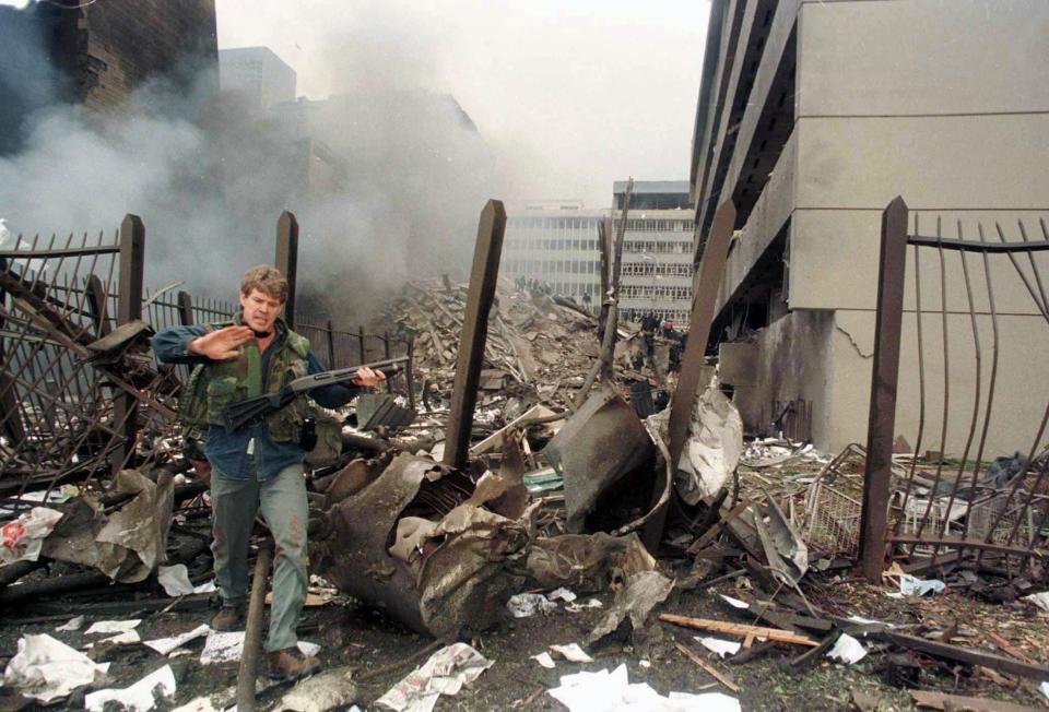 A U.S. embassy official secures the area around the embassy building after a powerful bomb blast in Nairobi in this file photo taken August 7, 1998. Senior al Qaeda figure Anas al-Liby, indicted by the United States for his alleged role in the 1998 bombings of U.S. embassies in East Africa, was captured in Libya by a U.S. team and is in American custody, U.S. officials said on Saturday. REUTERS/Antony Njuguna/Files (KENYA - Tags: CRIME LAW DISASTER POLITICS)