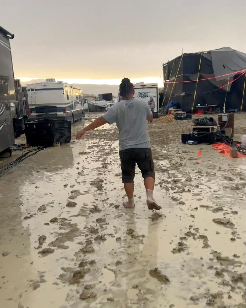 Un asistente camina por el barro después de una fuerte lluvia durante el evento Burning Man.