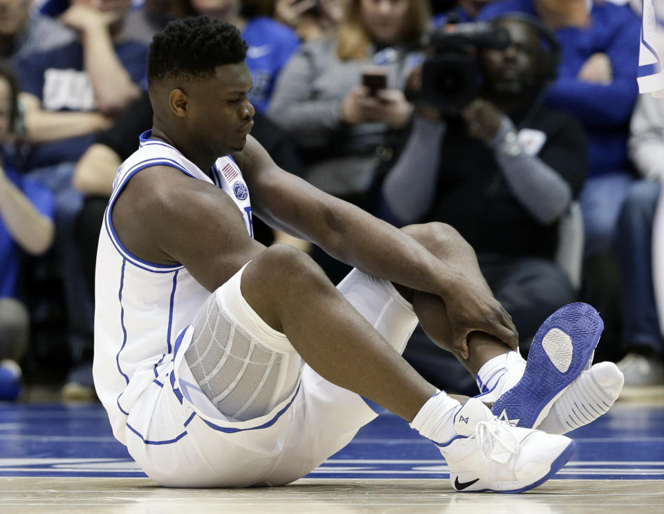 Duke's Zion Williamson sits on the floor following an injury during the first half of an NCAA college basketball game against North Carolina, in Durham, N.C., Wednesday, Feb. 20, 2019. Duke might have to figure out what the Zion Show will look like without its namesake. All because of a freak injury to arguably the most exciting player in college basketball. As his Nike shoe blew out, Williamson sprained his right knee on the first possession of what became top-ranked Duke's 88-72 loss to No. 8 North Carolina. (AP Photo/Gerry Broome)