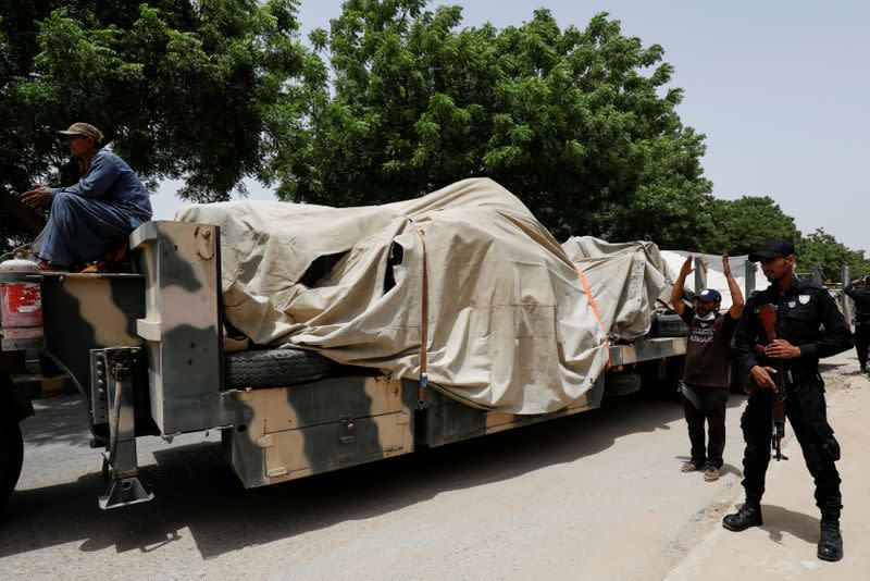 Police officer stands guard beside a truck loaded with the wreckage of the crashed plane, in Karachi