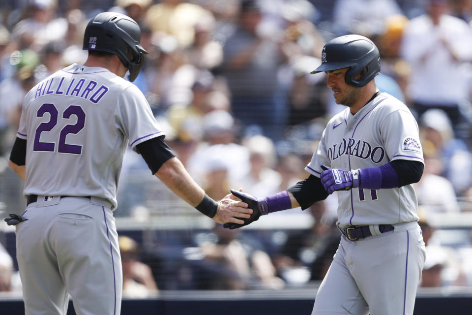 Colorado Rockies' Sam Hilliard, left, celebrates with Jose Iglesias, right, after crossing home plate on a two-RBI double by Ryan McMahon against the San Diego Padres during the eighth inning of a baseball game Sunday, June 12, 2022, in San Diego. (AP Photo/Mike McGinnis)