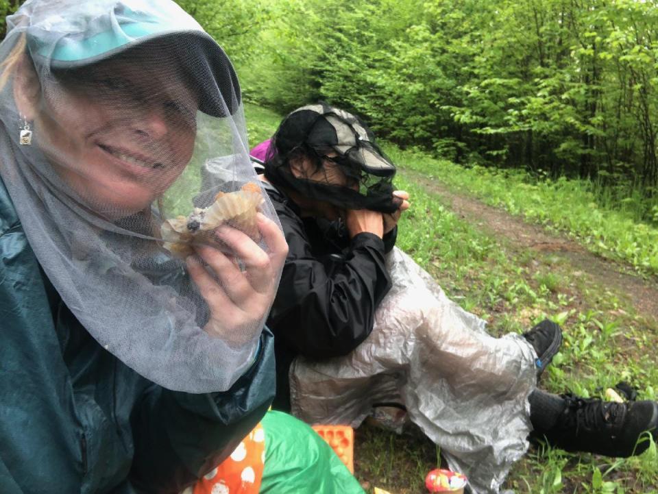 Arlette Laan, left, and Roberta Smith eat lunch while wearing headnets to fend off mosquitos while hiking the Ice Age Trail in northern Wisconsin in May 2022.