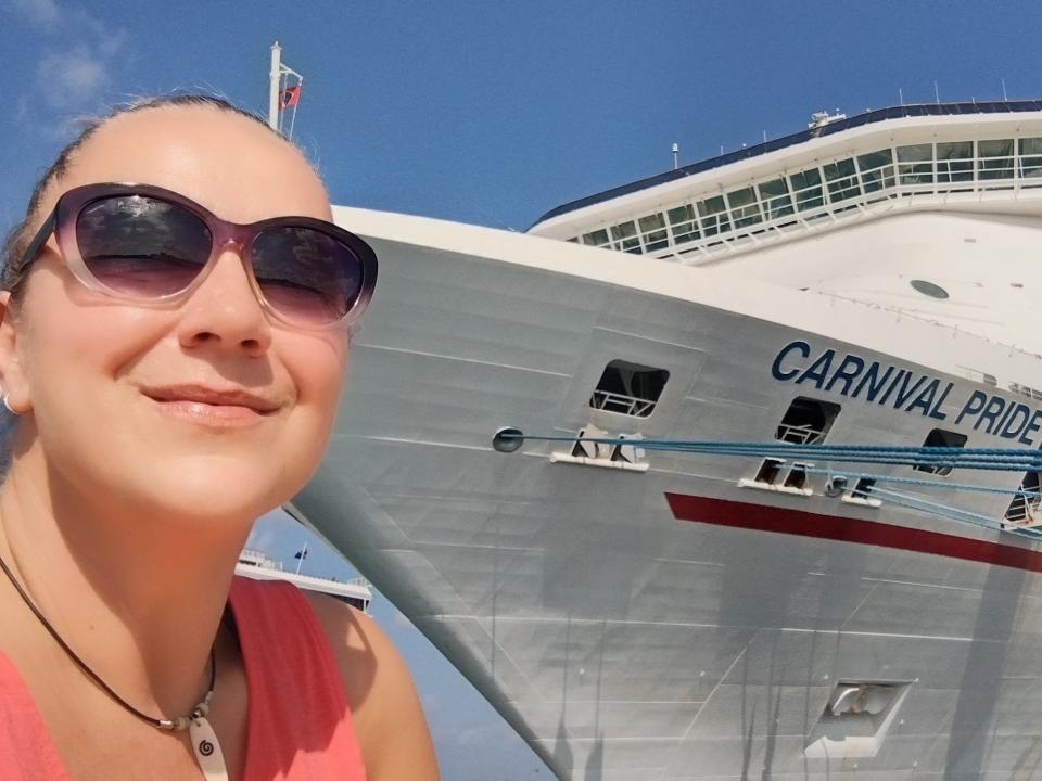 Woman posing for a selfie in front of Carnival Pride cruise ship Lori A. May mistakes first time cruisers make