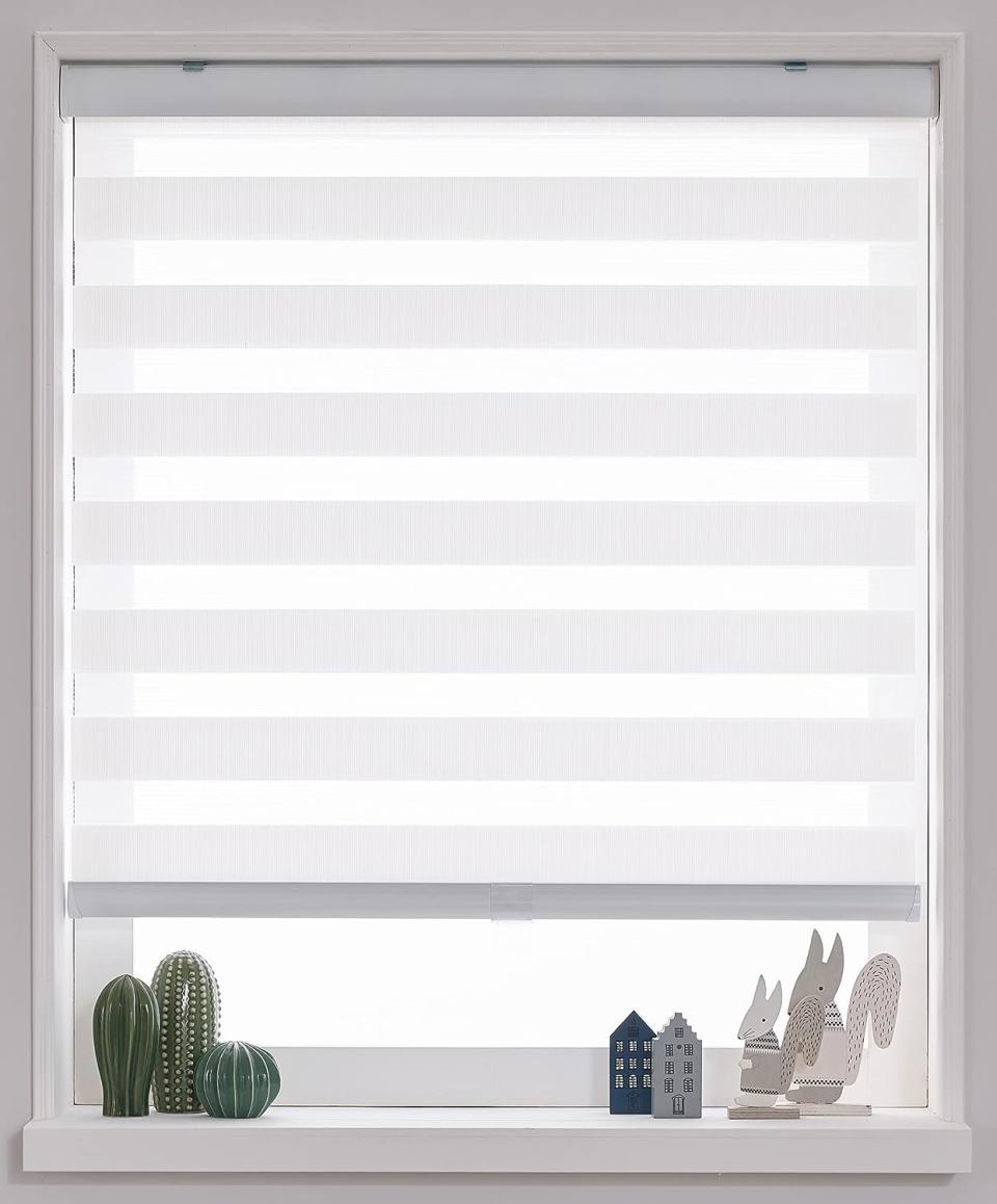 A set of roller blinds is pulled down to shade a white window.