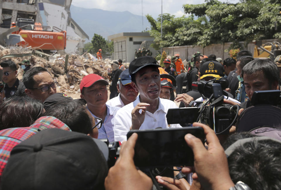 In this Wednesday, Oct. 3, 2018, photo, Indonesian President Joko Widodo, center, talks to media after visiting the earthquake and tsunami-damaged Roa-Roa Hotel. (AP Photo/Tatan Syuflana)