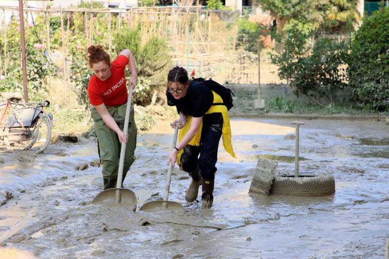 Photo of two people shoveling mud