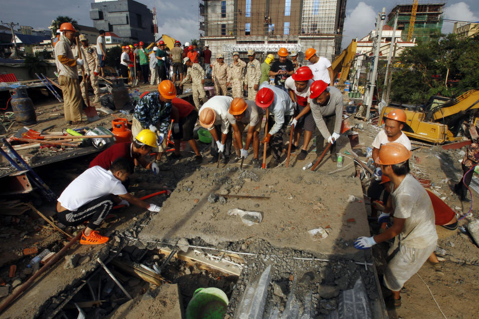 Rescuers try to remove the rubble at the site of a collapsed building in Preah Sihanouk province, Cambodia, Sunday, June 23, 2019. Rescue workers were using saws to cut steel beams and excavators to move piles of rubble of the collapsed seven-story building. (AP Photo/Heng Sinith)