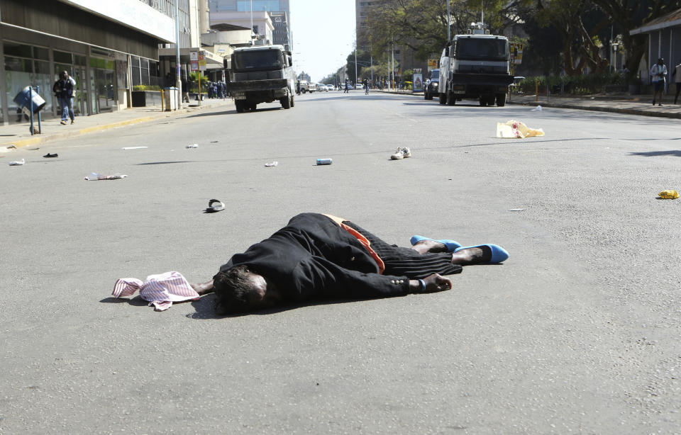 A woman lies in the road after been injured by police during protests in Harare, Friday, Aug, 16, 2019. The main opposition Movement For Democratic Change party is holding protests over deteriorating economic conditions in the country as well as to try and force Zimbabwean President Emmerson Mnangagwa to set up a transitional authority to address the crisis and organize credible elections. (AP Photo/Tsvangirayi Mukwazhi)