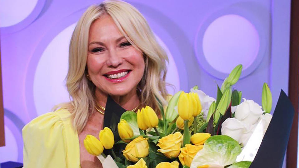 Kerri-Anne Kennerley wearing a yellow top and holding a bunch of yellow tulips