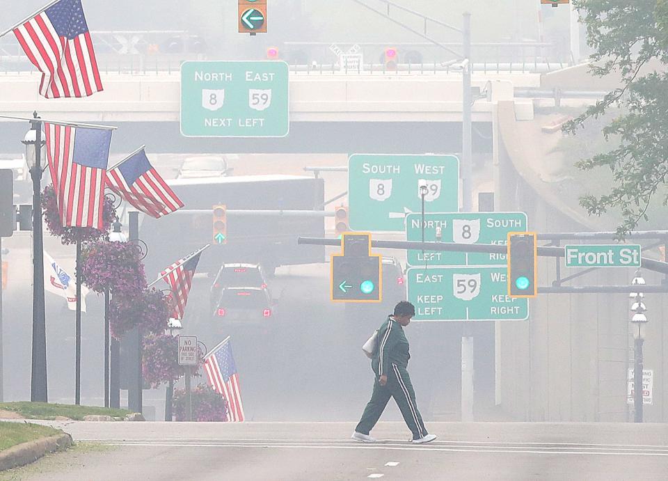 A pedestrian walks across Broad Boulevard at Second Street through the mid-morning haze  June 28 in Cuyahoga Falls.