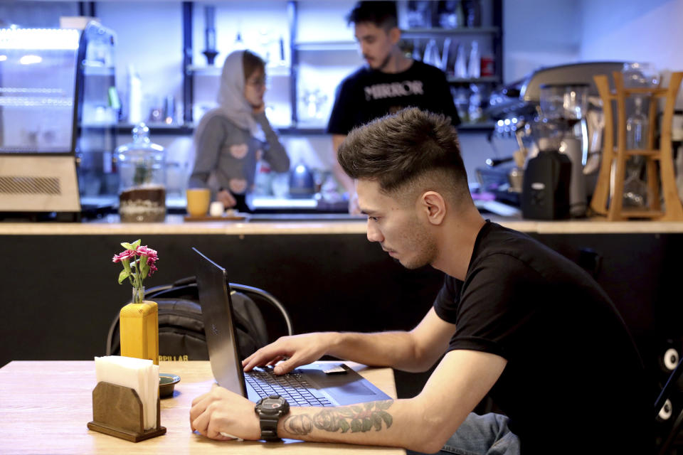 In this Monday, Oct. 7, 2019 photo, an Afghan refugee uses a computer at an Afghan cafe in downtown Tehran, Iran. More than 3 million Afghans including as many as 2 million who entered without legal permission, live in the Islamic Republic, according to United Nations estimates. Fatemeh Jafari, a 21-year-old Afghan refugee, hopes her Telma, or "Dream," Café in Tehran will help bridge the divides and xenophobia Afghans can face in Iran. (AP Photo/Ebrahim Noroozi)