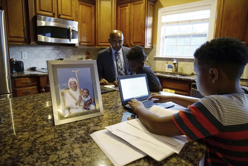 Tewodrose Tirfe helps his sons, Ymesgen, 10, left, and Adane, 12, with their homework in the kitchen of their home in Harrisburg, N.C., on Thursday, Oct. 21, 2021. Tirfe is chairman of the Amhara Association of America, an advocacy group for Ethiopia's second-largest ethnic group. (AP Photo/Allen G. Breed)