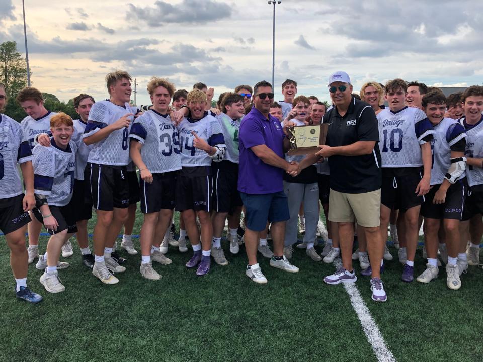 Rumson-Fair Haven's Vice Principal of athletics and student activities Chris Lanzalotto (purple shirt) hands the  NJSIAA Group 2 State Final trophy to Rumson-Fair Haven boys lacrosse coach Marc Moreau as the players surrounded them. Rumson-Fair Haven defeats Summit in the NJSIAA Group 2 State Final on June 3, 2022 at Rumson-Fair Haven Regional High School