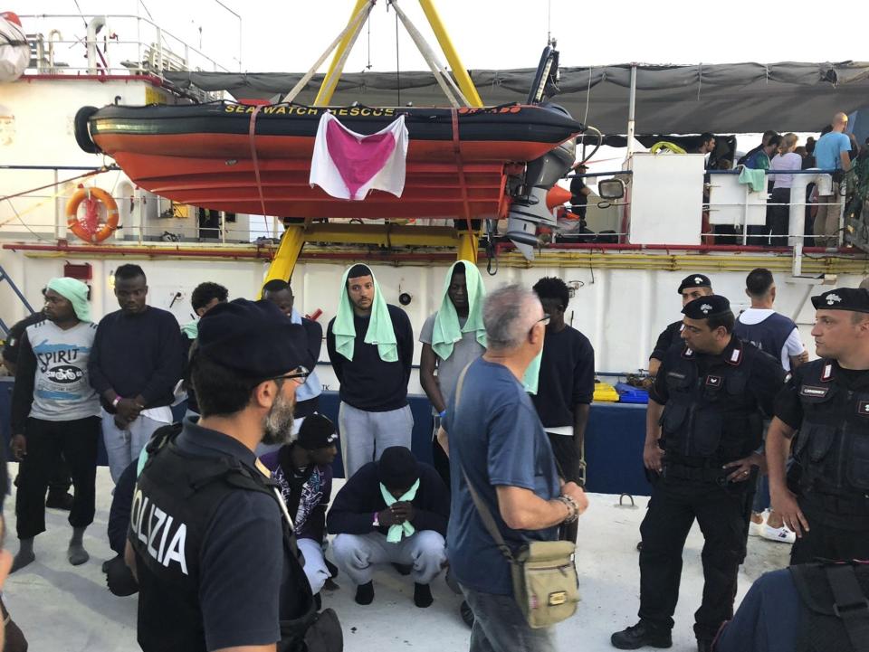 Migrants stand on the quay after disembarking from the Dutch-flagged Sea-Watch 3 ship, at the Lampedusa harbor, Italy, Saturday, June 29, 2019. Forty migrants have disembarked on a tiny Italian island after the captain of the German aid ship which rescued them docked without permission. Sea-Watch 3 rammed an Italian border police motorboat as it steered toward the pier on Lampedusa. (AP Photo/Annalisa Camilli)