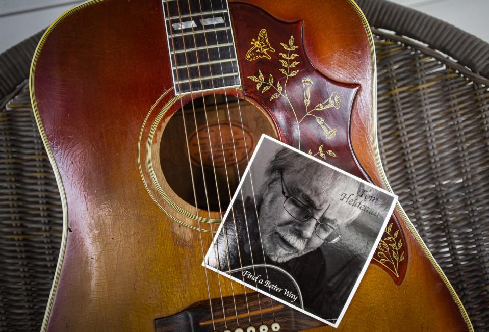 Tom Heiderman's newly-released "Find a Better Way" five-song EP,  and his 1964 Gibson Hummingbird acoustic guitar, pictured Monday, Aug. 7, 2023, on the front porch of his home in Lansing. Heiderman's song addresses the pervasiveness of gun violence in today's society.