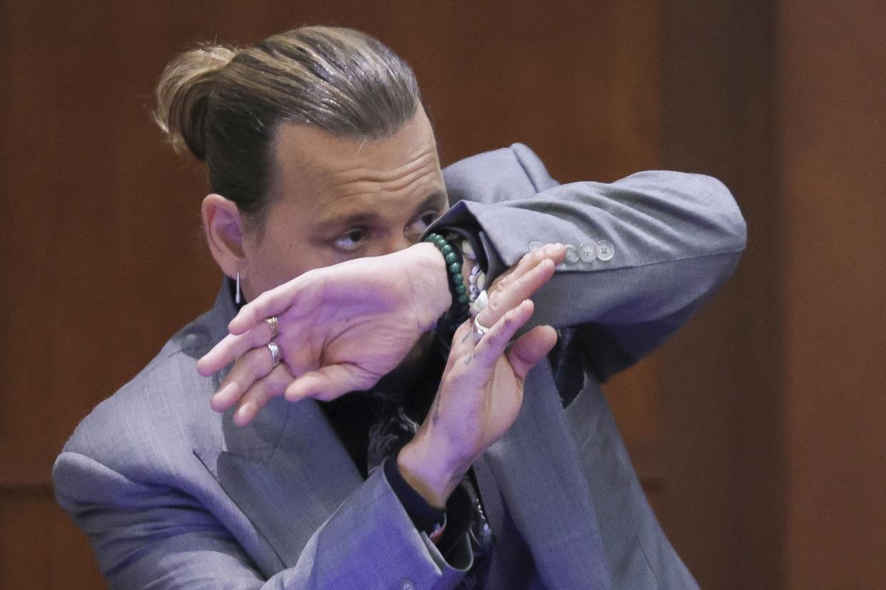 Actor Johnny Depp demonstrates how he claims to have shielded himself from an alleged attack by his ex-wife Amber Heard as he testifies during the trial at the Fairfax County Circuit Court in Fairfax, Va. on Wednesday, April 20, 2022.