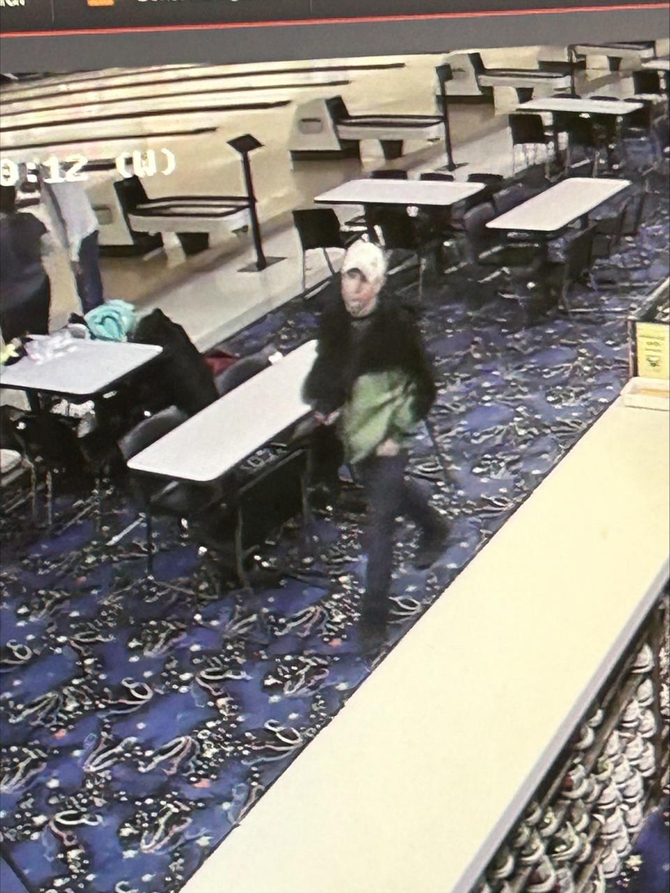In a screen shot taken from security footage, the man identified by police as a suspect in a theft at Century Bowl walks past the front desk. He's carrying a jacket from a pest control company that Century Bowl employees say they found in the trash.