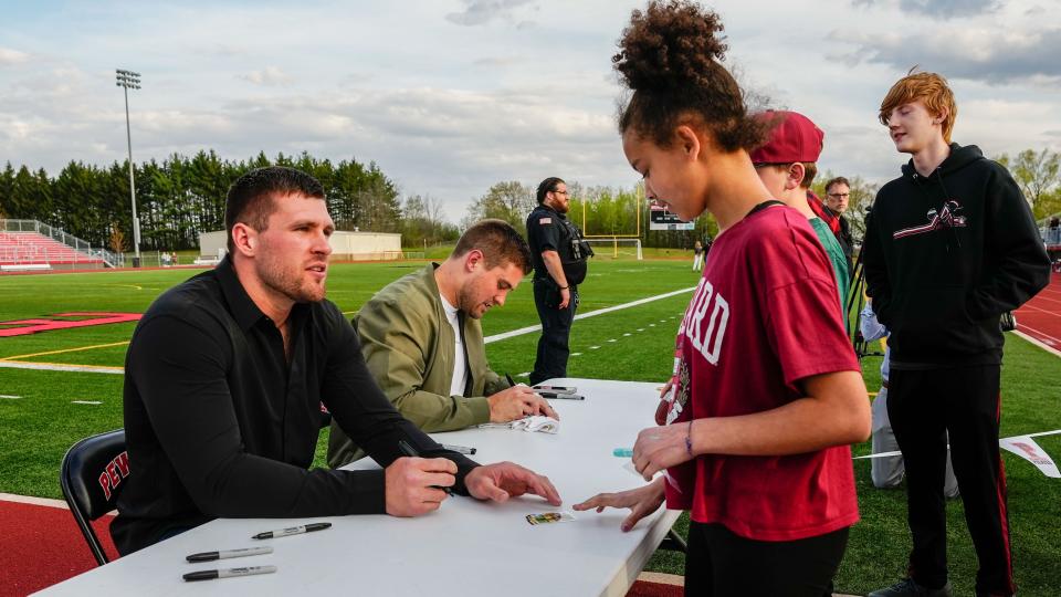 Brothers TJ, left, and Derek Watt, sign memorabilia for youngsters after their jersey retirement ceremony at Pewaukee High School, Friday, May 5, 2023.