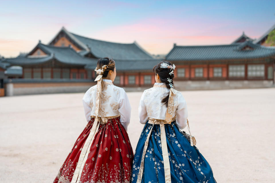 Two lovely women in hanbok stroll through the traditional-style homes of Seoul's Village.
