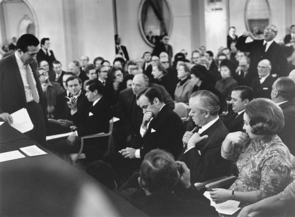 <div class="inline-image__caption"><p>Rival publishers Robert Maxwell (standing, left) and Rupert Murdoch (center) await a vote on their respective bids for the <em>News Of The World</em> newspaper, during a shareholders' meeting at the Connaught Rooms, London, January 2, 1969. The shareholders are to vote on whether to accept a share exchange deal with Murdoch's company, News Ltd, or approve a 34 million pound takeover bid by Pergamon Press, owned by Maxwell. The vote later went in favor of Murdoch's offer. </p></div> <div class="inline-image__credit">Aubrey Hart/Evening Standard/Hulton Archive/Getty</div>