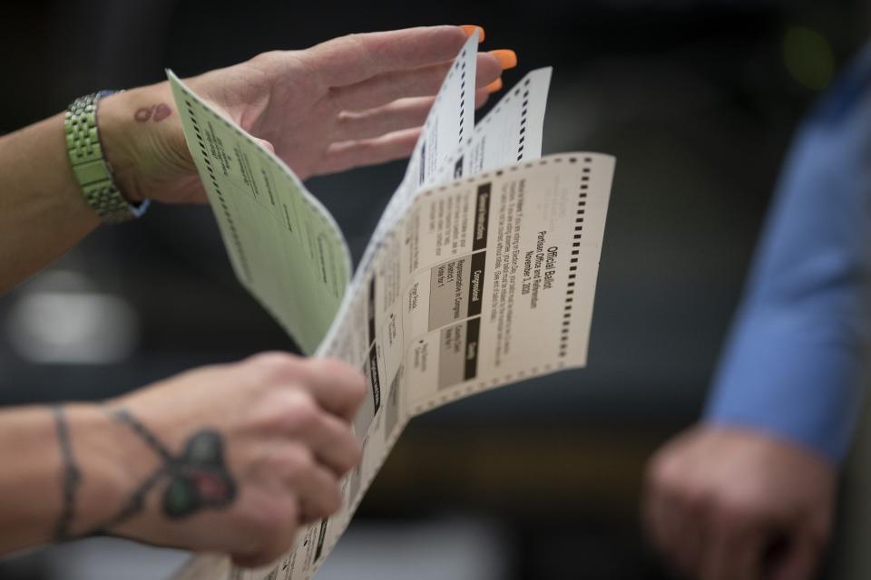 FILE - Poll workers sort out early and absentee ballots at the Kenosha Municipal building on Election Day in Kenosha, Wis., on Nov. 3, 2020. Disabled voters who need assistance submitting absentee ballots say communities across Wisconsin are not following federal law in the lead up to the high-stakes state Supreme Court election, incorrectly telling those with disabilities that they can't have another person return their ballot for them. The April 4 election will determine majority control of the state Supreme Court. (AP Photo/Wong Maye-E, File)